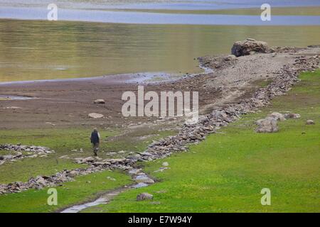 Parco Nazionale del Distretto dei Laghi, Cumbria, Regno Unito. 24Sep, 2014. Uomo che cammina attraverso le rovine del villaggio di Mardale emerge da Hawswater, Parco Nazionale del Distretto dei Laghi, Cumbria, Regno Unito. Credito: Andrew Findlay/Alamy Live News Foto Stock