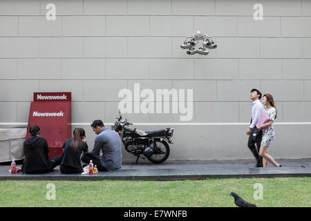 Persone sedersi da una banca di telecamere di sicurezza nel quartiere centrale degli affari di Singapore. Foto Stock