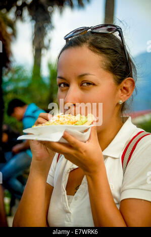 Giovane e bella ragazza a mangiare una tostada soft taco Foto Stock