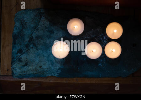 Candele emettono una luce calda su un santuario buddista Foto Stock