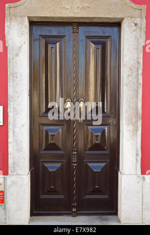 Brown porta nel centro storico della città di Tavira hanno poco in ottone maniglie della porta a forma di mani. Foto Stock