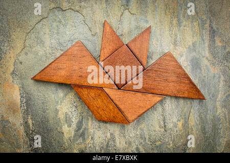 Immagine astratta di un flying bat costruito da sette tangram pezzi di legno su una roccia di ardesia sfondo, concetto di Halloween Foto Stock