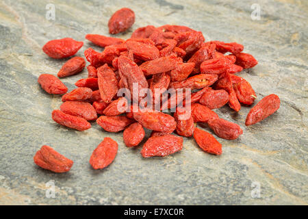 Un mucchio di essiccato Tibetan goji bacche (wolfberry) su una roccia di ardesia superficie Foto Stock