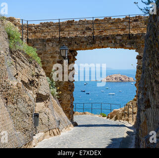 Vista verso Tossa bay attraverso il telaio passa in fortezza "Vila Vella enceinte" della Citta Vecchia di Tossa de Mar, la Catalogna. Foto Stock