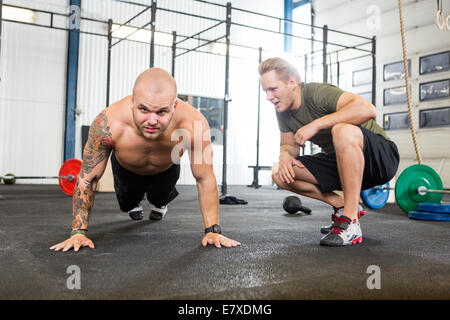 Il trainer assiste l uomo nel fare pushups Foto Stock