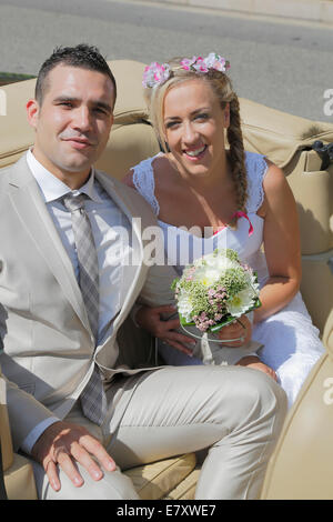Sposa e lo sposo in posa sul sedile posteriore di una vettura aperta, convertibile Foto Stock