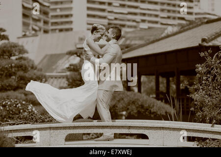 Lo sposo sollevando la sposa in aria Foto Stock