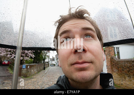 L'uomo rifugiandosi sotto ombrellone Foto Stock