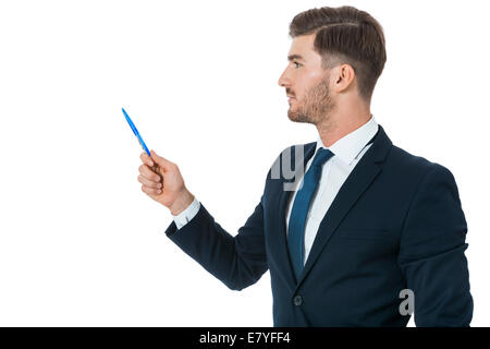 Elegante giovane impreditore facendo una presentazione, effettuare una selezione o mostrando qualcosa che puntano verso la sinistra del telaio con una penna in mano come egli si trova lateralmente alla telecamera, isolato su bianco Foto Stock