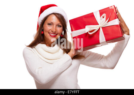 Pretty Woman in una festa di Santa Red hat con un grande rosso corrispondente regalo di Natale legate con un nastro e la prua tenendola davanti Foto Stock