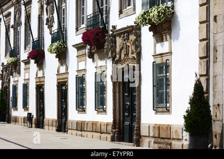 Porta ornata in pietra scolpita e facciata della casa de Carreira e dei gerani nella finestra, Viana do Castelo, Portogallo settentrionale Foto Stock