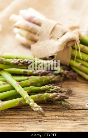 Fresco e salutare gli asparagi verdi spears legate in fasci su un rustico di legno sulla superficie di visualizzazione in un mercato degli agricoltori per la cottura di un delic Foto Stock