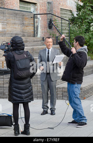 Newscaster con fotocamera e audio di equipaggio sulla linea alta park marciapiede in NYC. Foto Stock