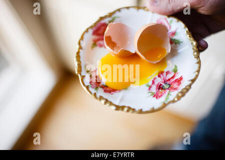 Vista in elevazione di rotture di guscio d'uovo e il tuorlo d'uovo sulla piastra Foto Stock