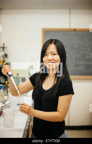 Donna in laboratorio con pipetta del bocchettone di rifornimento e di tubo di vetro Foto Stock