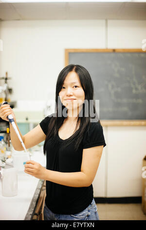 Donna in laboratorio usando una pipetta di riempimento e tubo di vetro Foto Stock