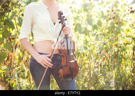 La sezione centrale colpo di giovane donna con violino nel campo di girasoli Foto Stock