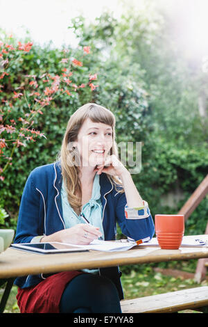 Donna seduta all'aperto con i tablet pc Foto Stock