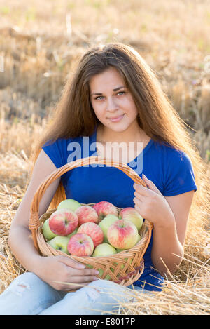 Teen ragazza con un cesto di mele nel campo Foto Stock