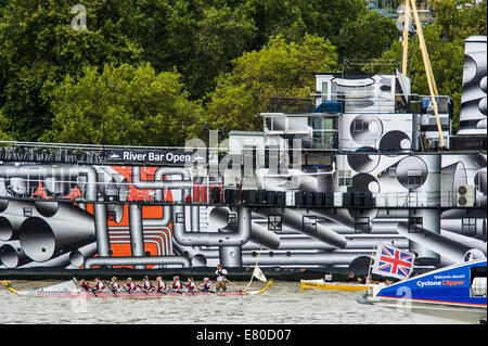 Barche di passare il dispositivo HMS Presidente che è stato verniciato in 'Dazzle' camuffamento di vernice in commemorazione di WW1, il grande fiume gara, London's River Marathon (noto anche come il Regno Unito barca tradizionale campionato) - Un 21,6 miglia gara in barca lungo il fiume Tamigi da Docklands di Londra al prosciutto in Surrey. Esso attrae oltre 300 equipaggi provenienti da tutto il mondo e fa appello ad ogni livello del concorrente di coloro che godono di divertimento, Fancy Dress e carità di acrobazie, a gravi sportivi. Il fiume Tamigi, Londra, 27 settembre 2014. Foto Stock