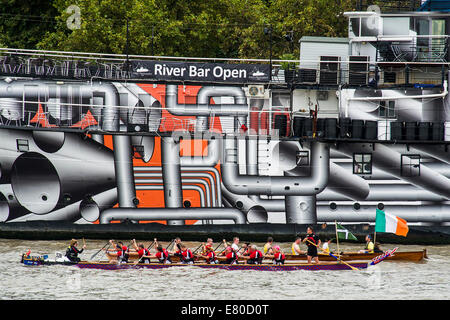 Barche di passare il dispositivo HMS Presidente che è stato verniciato in 'Dazzle' camuffamento di vernice in commemorazione di WW1, il grande fiume gara, London's River Marathon (noto anche come il Regno Unito barca tradizionale campionato) - Un 21,6 miglia gara in barca lungo il fiume Tamigi da Docklands di Londra al prosciutto in Surrey. Esso attrae oltre 300 equipaggi provenienti da tutto il mondo e fa appello ad ogni livello del concorrente di coloro che godono di divertimento, Fancy Dress e carità di acrobazie, a gravi sportivi. Il fiume Tamigi, Londra, 27 settembre 2014. Foto Stock