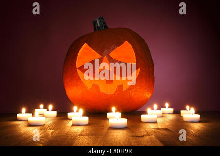 La zucca su uno sfondo rosso con candele per Halloween Foto Stock