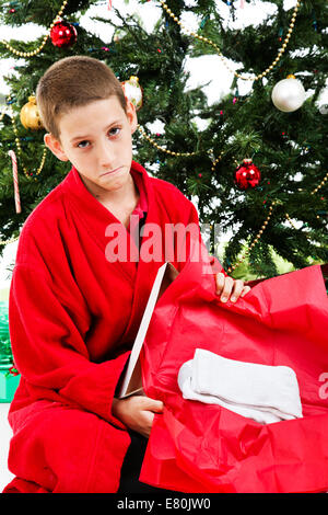 Little Boy apertura avvolto un presente di calze sulla mattina di Natale. Foto Stock