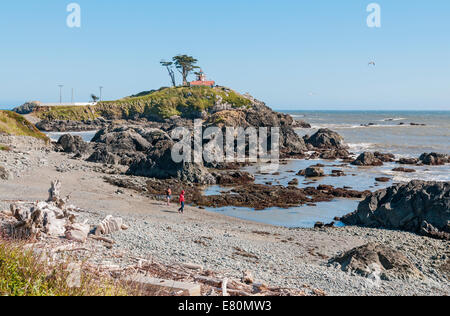 California, Crescent City, Batteria Point Lighthouse costruito 1856, giovane con due cani giocando sulla spiaggia Foto Stock