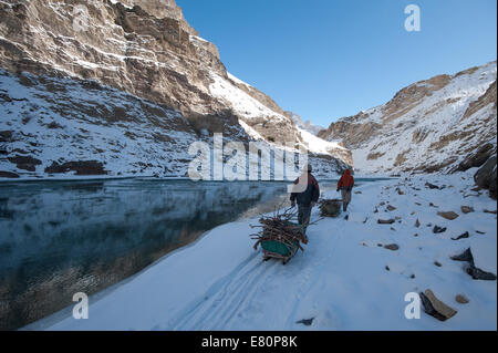 Due facchini sono tirando il trekking di bagagli sul fiume Zanskar durante Chadar trek Foto Stock