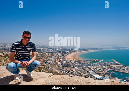 Ritratto orizzontale di un giovane marocchino uomo con una veduta aerea di tutta la sua città natale di Agadir Foto Stock