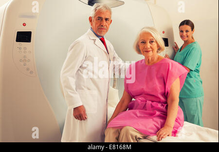 Donna in 60s pronto per essere controllato sotto scanner MRI con i senior medico e sorridente assistente femmina. Foto Stock