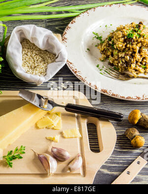 Gli ingredienti di italiano il risotto con funghi disposti su una tavola di legno Foto Stock