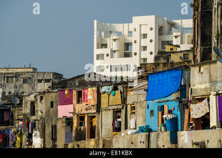 Le abitazioni tipiche dei poveri classe operaia Indiani nella parte anteriore di un moderno palazzo residenziale, Mumbai, Maharashtra, India Foto Stock