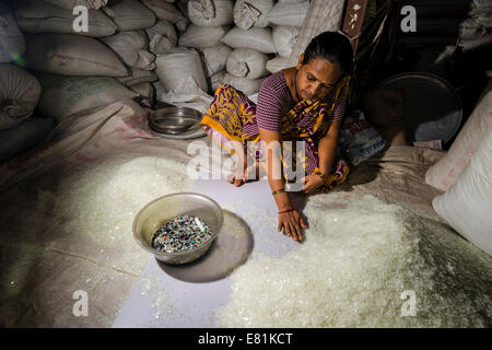 Donna di smistamento di shredded white immondizia di plastica per il riciclaggio, Dharavi Slum, Mumbai, Maharashtra, India Foto Stock