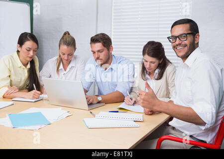 Business uomo sorridente in telecamera dando pollice in alto Foto Stock