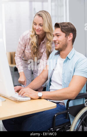 Casual imprenditrice aiutando il collega in sedia a rotelle Foto Stock