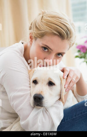 Felice bionda cuddling con cucciolo sul divano Foto Stock