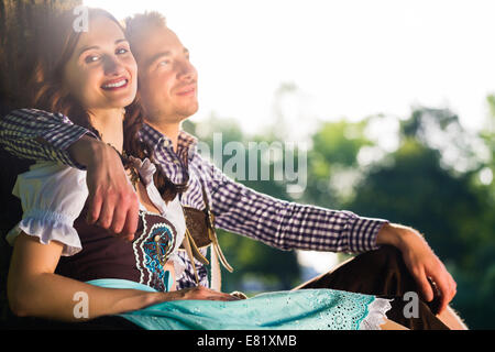 Coppia bavarese in Tracht abbracciando sotto agli alberi Foto Stock