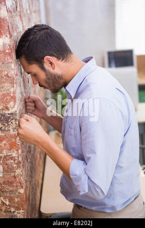 Considerato giovane imprenditore in piedi contro il muro Foto Stock