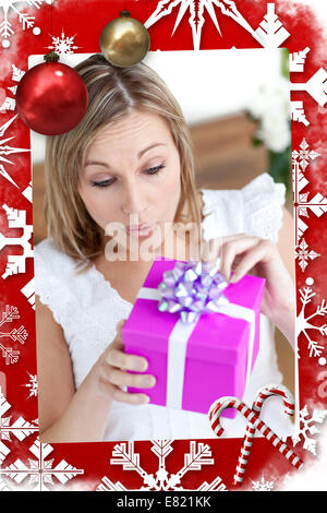 Sorpreso donna apre un regalo seduta sul pavimento Foto Stock