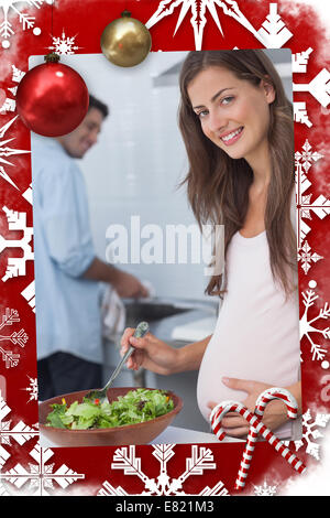 Donna incinta preparare una insalata in cucina Foto Stock