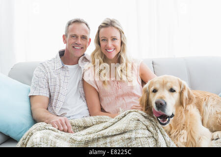 Affettuosa giovane seduto sul divano sotto una coperta con il loro cane Foto Stock