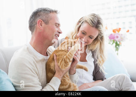 Coppia sorridente petting loro gringer cat sul lettino Foto Stock