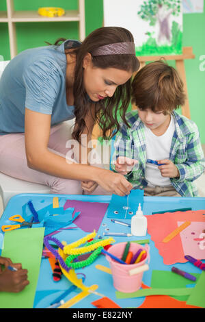 Piuttosto insegnante aiutando la pupilla in aula Foto Stock