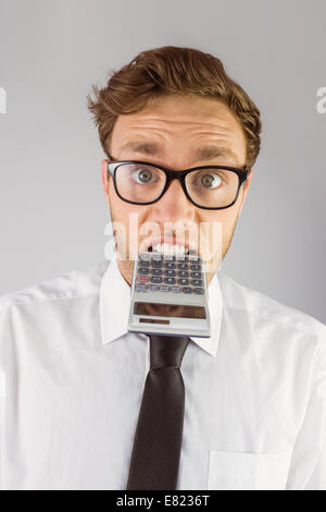 Geeky imprenditore mordere una calcolatrice Foto Stock