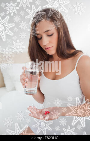 Donna che guarda verso il basso in corrispondenza delle due pillole sta andando a prendere con acqua Foto Stock