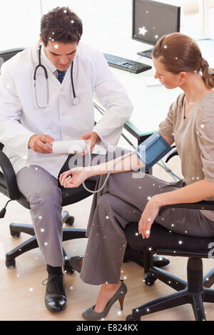 Vista laterale del medico tenendo i suoi pazienti la pressione sanguigna Foto Stock