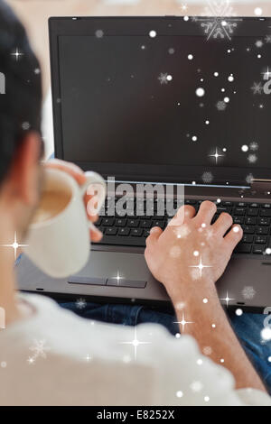 Sulla spalla vista del giovane uomo usando il suo computer portatile Foto Stock