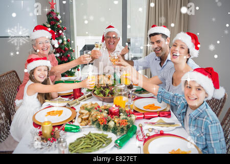 La famiglia in cappelli di Babbo Natale tostatura di bicchieri di vino al tavolo da pranzo Foto Stock