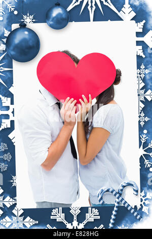 Immagine composita della giovane per la copertura del loro bacio con un cuore Foto Stock